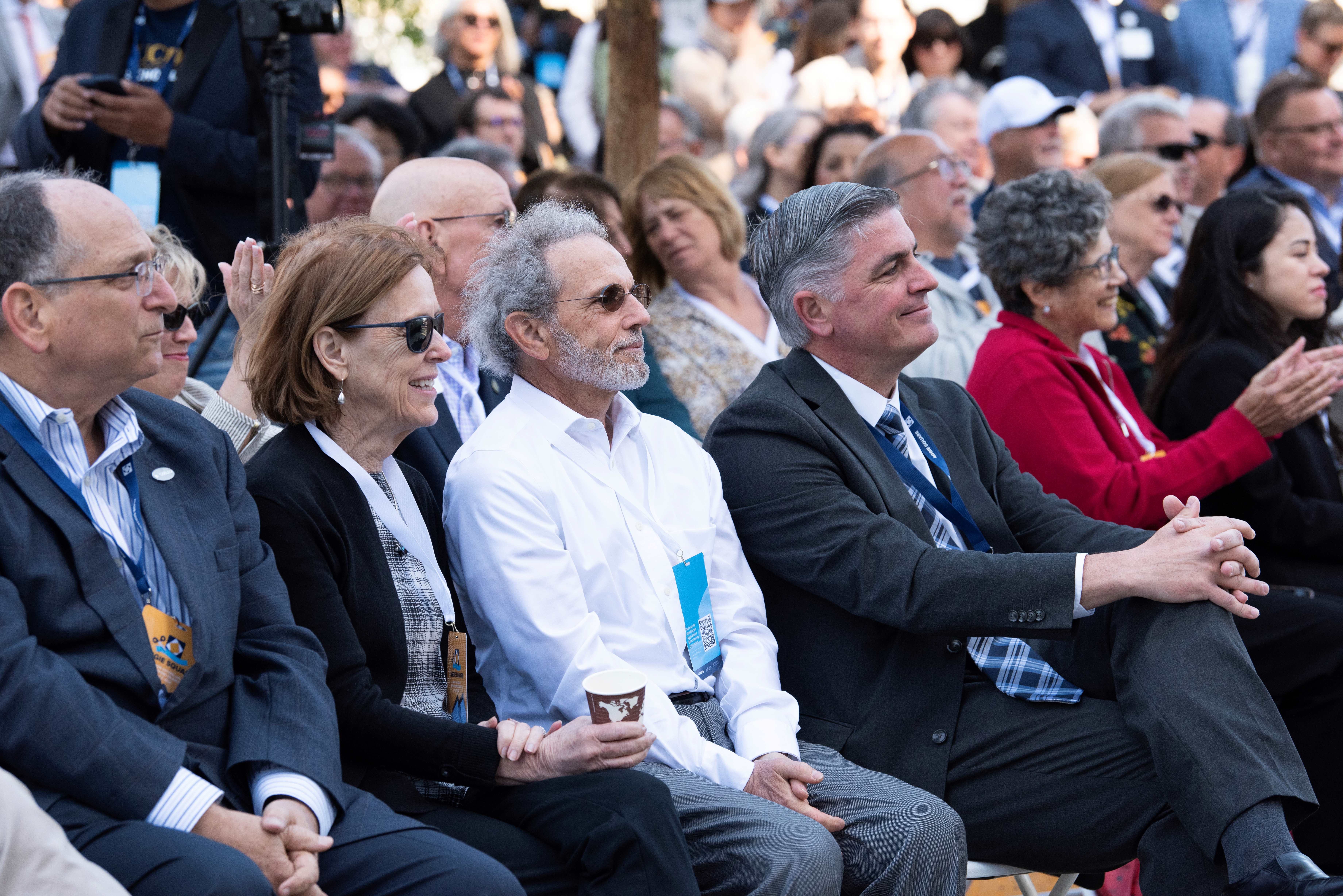 People sit in a crowd listening to a speech.