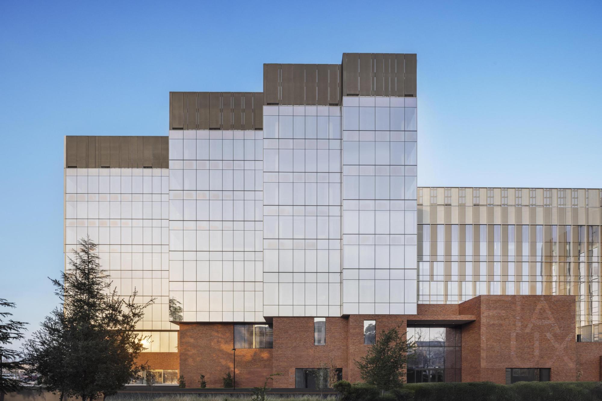Building made of brick and glass. The words "fiat lux" are spelled out in one of the brick walls.