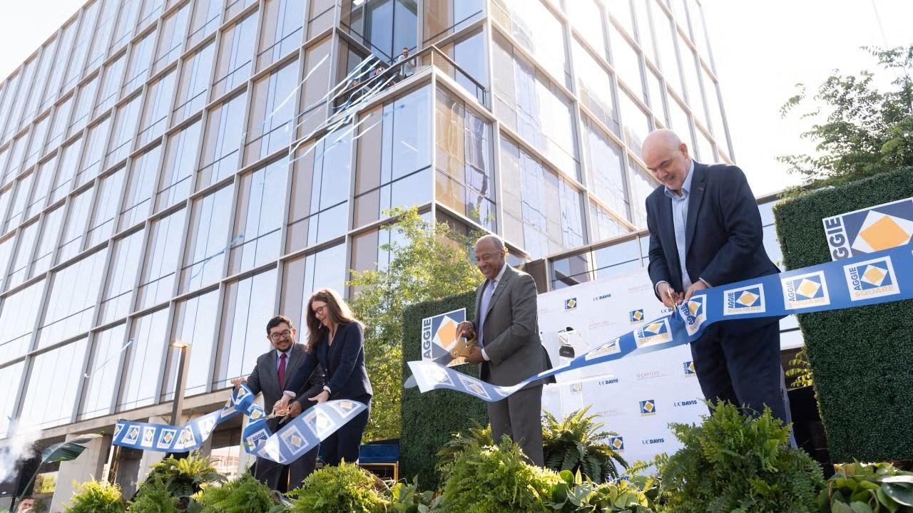 People cut a ribbon outside a building marking the grand opening of Aggie Square.