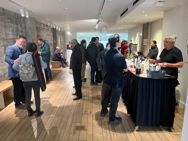 People stand near a beverage table chatting.
