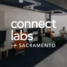 Darkened image of an office space with the words "Connect Labs - Sacramento" written in white lettering over it.