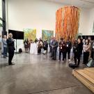 A crowd of people listens to a speaker in a modern indoor space with colorful decor.